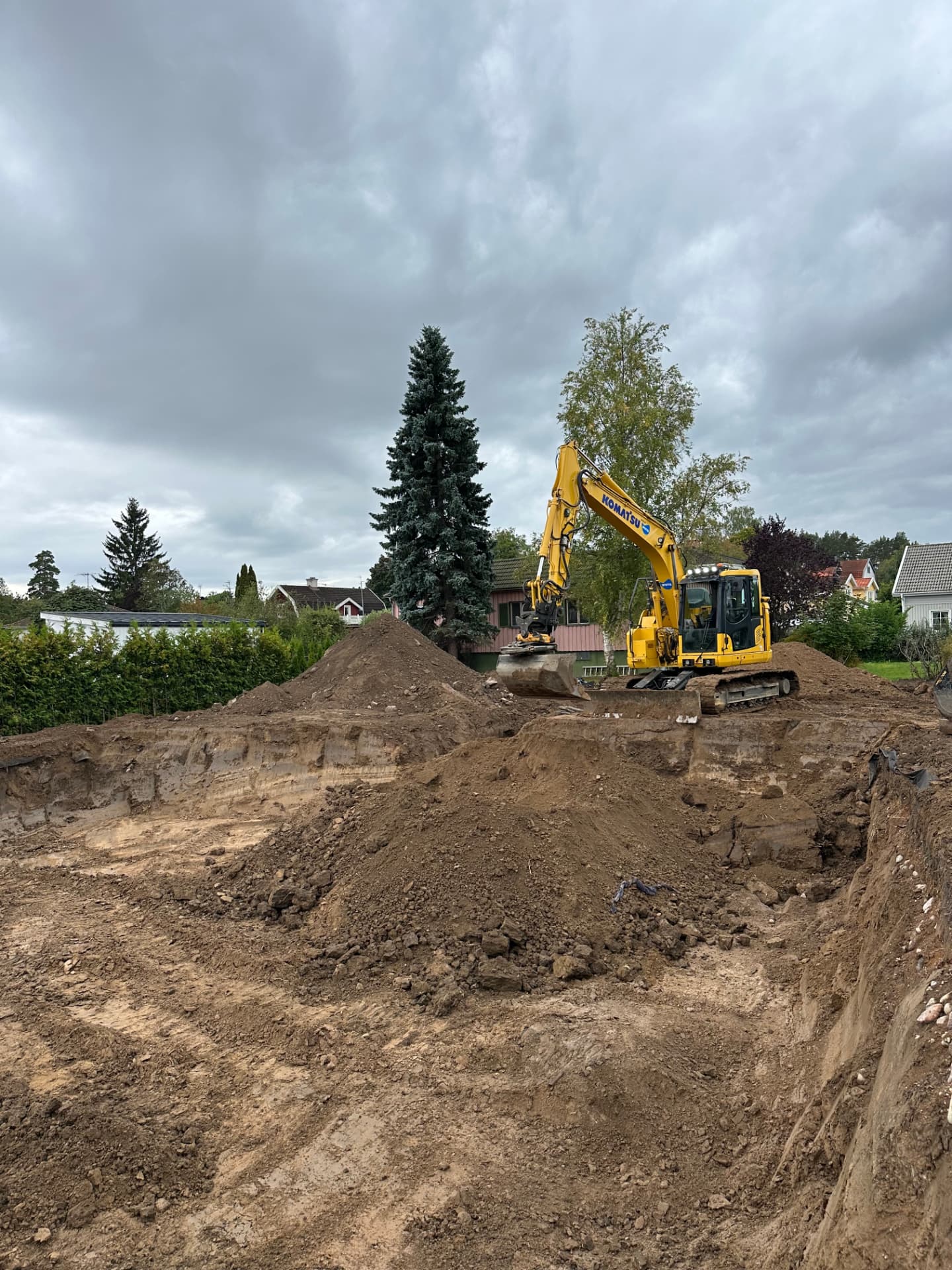 Komatsu grävmaskin vid schaktbotten för husgrund